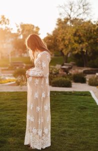 mom holding top of baby bump in intimate boho maternity session