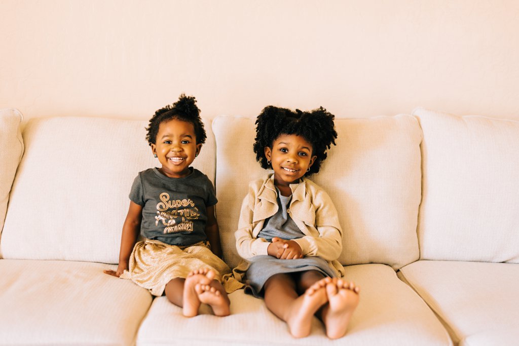 two sisters smiling while sitting on couch