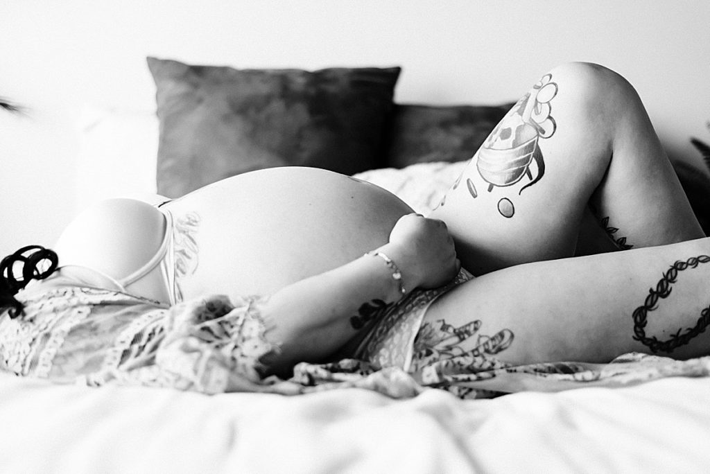 closeup of baby bump with mom laying on bed in black and white