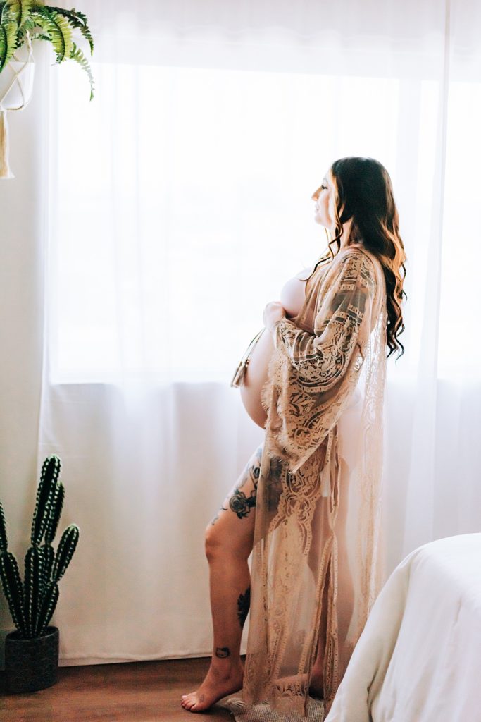 expecting mom in lace kimono gazing outwindow