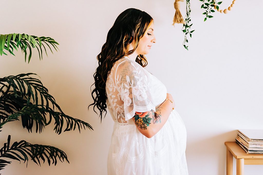 expecting mom in white lace dress by houseplants