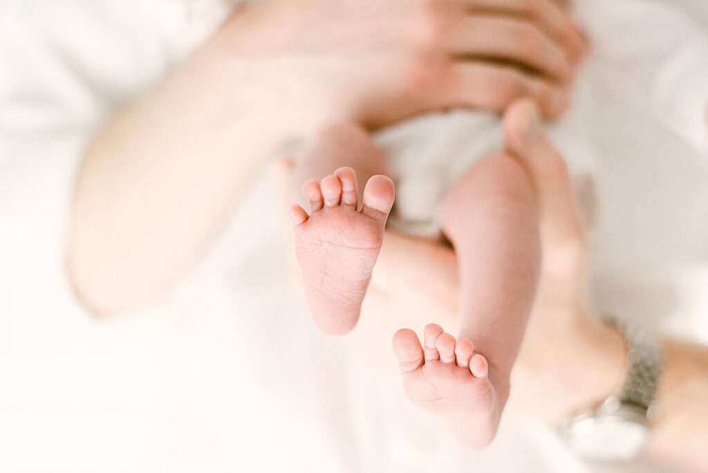 Closeup of newborn baby toes being held in dad's hands
