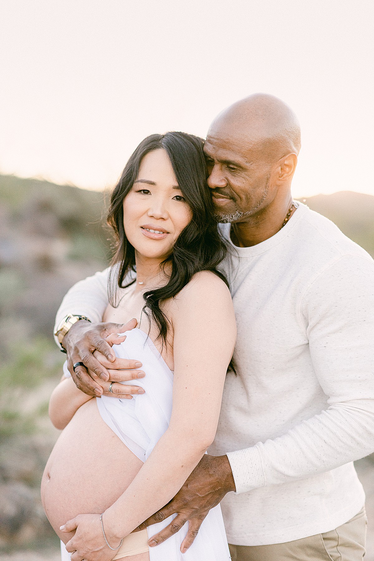 Mom and dad embraced and holding baby bump during maternity session