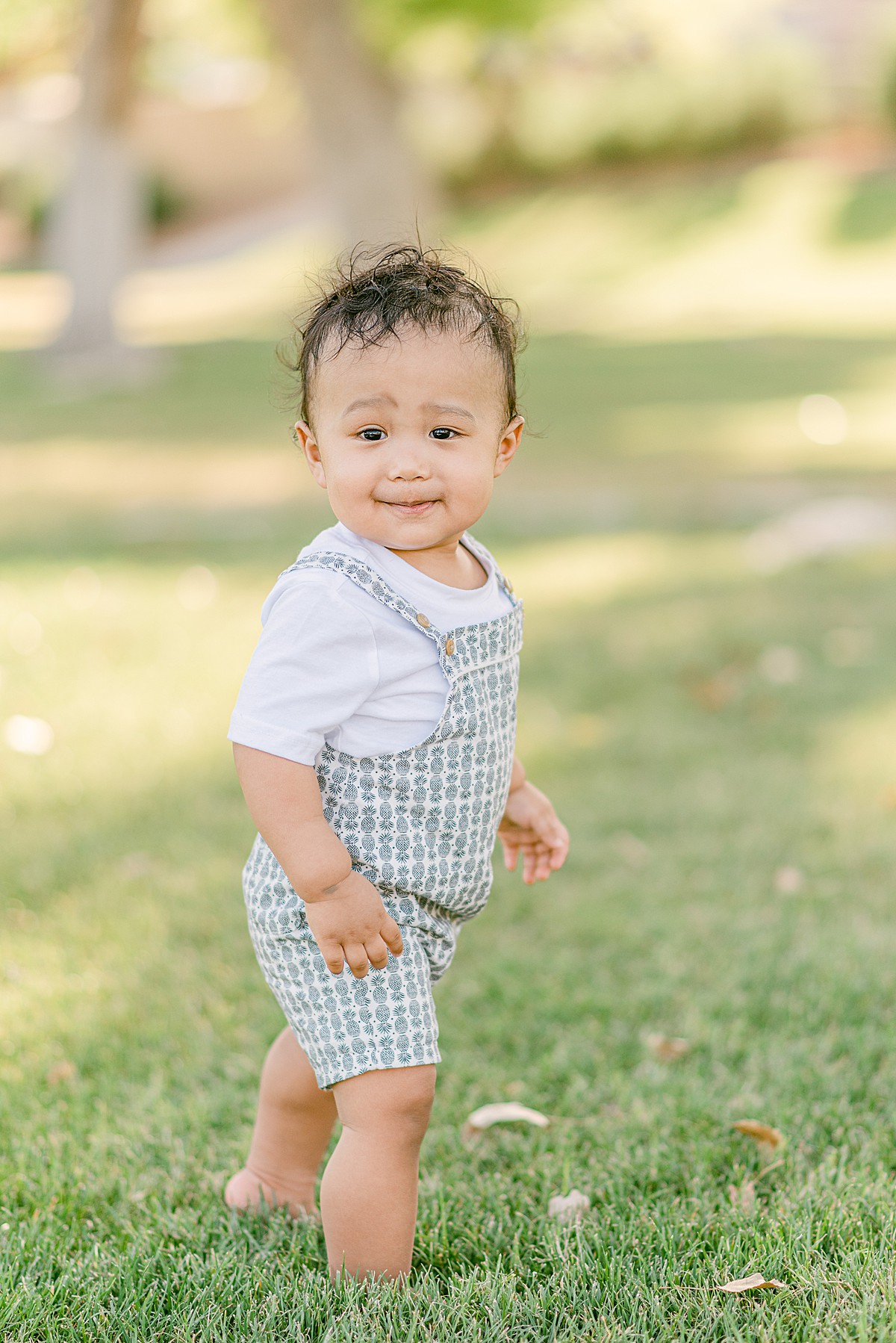phoenix baby photographer capturing One year old boy wearing overalls and standing in grass
