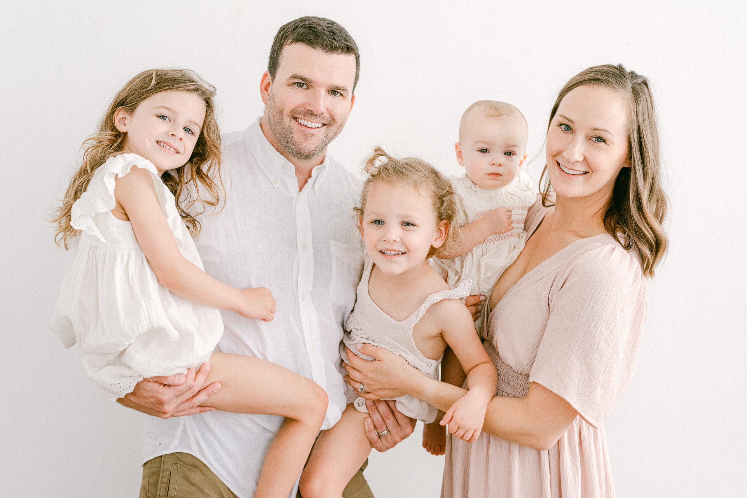 Gilbert family of five dressed in neutral colors for photoshoot in studio.
