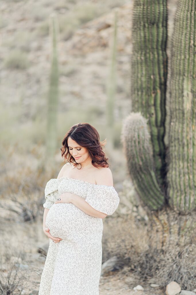 closeup of pregnant woman next to saguaro who knew when to take maternity photos to accentuate her bump. 