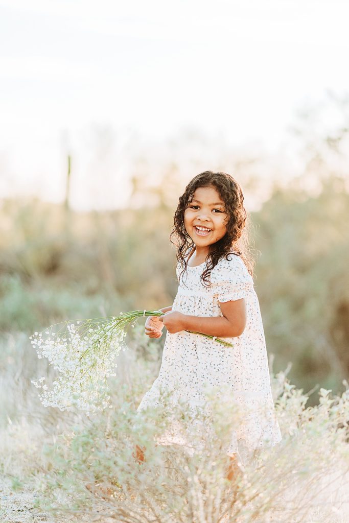 toddler girl playing with flowers in desert
