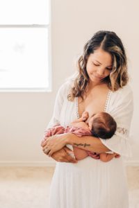 mom breastfeeding baby during in-home newborn photoshoot