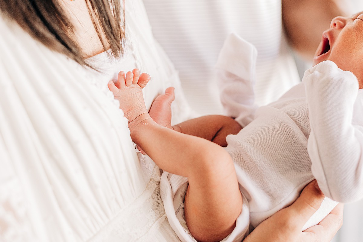 yawning newborn baby's feet on mom's chest