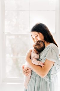 New mom holding newborn baby in natural light home