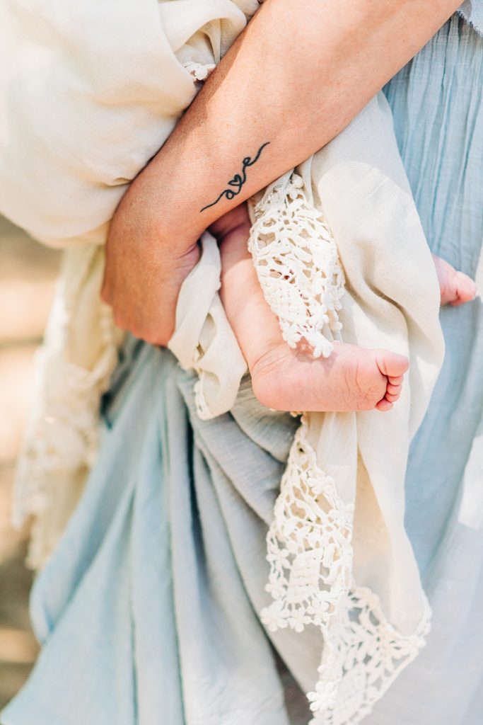 Closeup of 6 month old's feet while being held by mom during breastfeeding photoshoot.