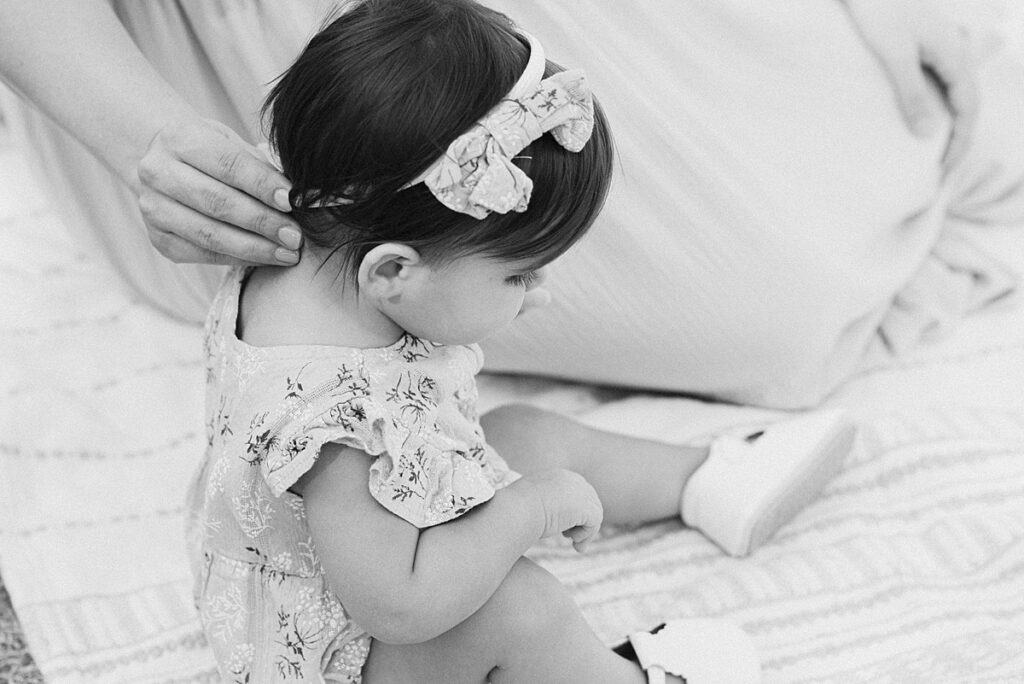 Closeup of mom's hand on the back of baby girl's hair strands. 