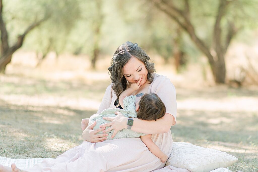 Baby touching mom's teeth making mom smile while breastfeeding.