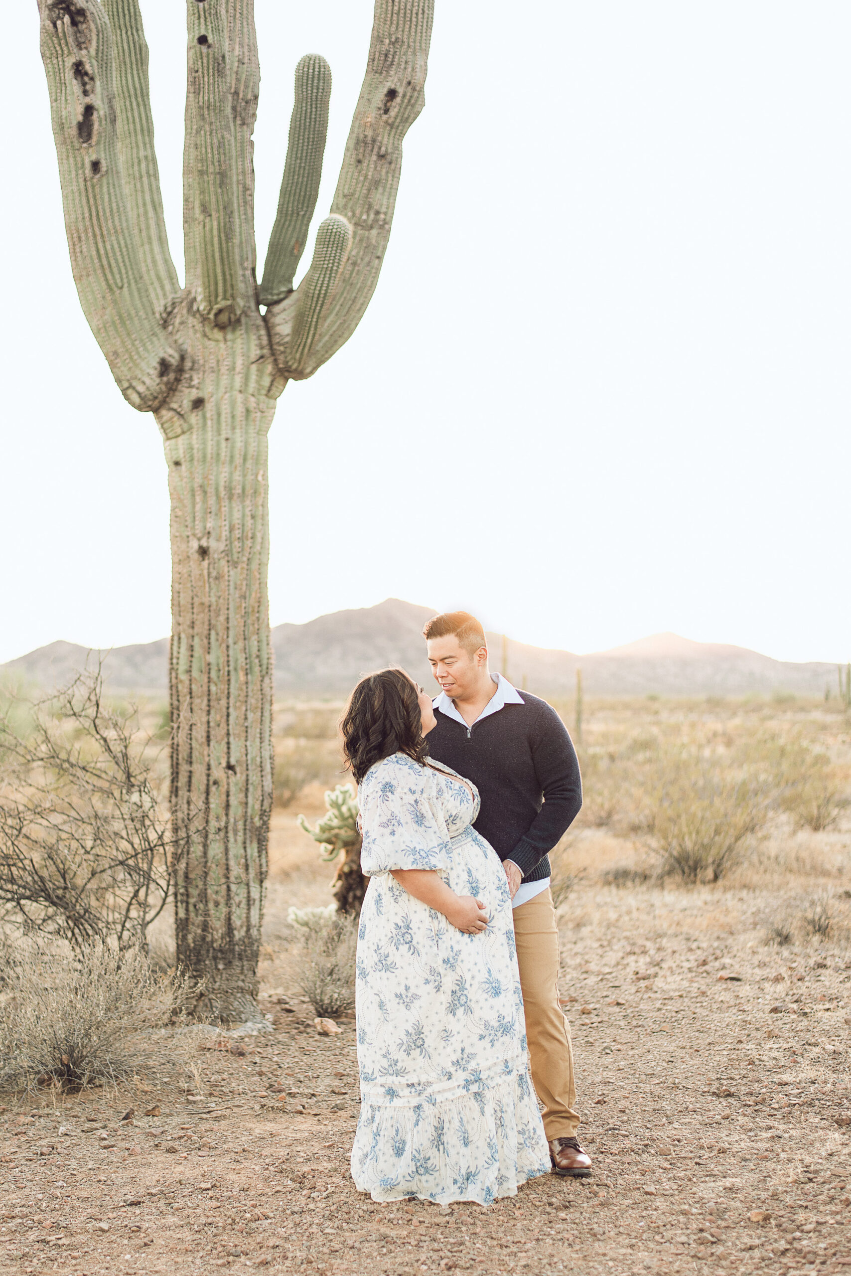 Maternity couple embraced during golden hour sunset at Apache Wash Trailhead