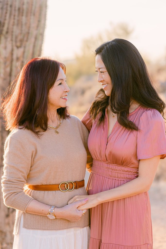 adult mom and daughter facing each other while holding hands for a family photo shoot in the desert