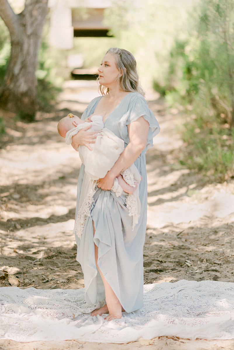 Mom dressed in flowy gown at Queen Creek Wash while breastfeeding 6 month baby