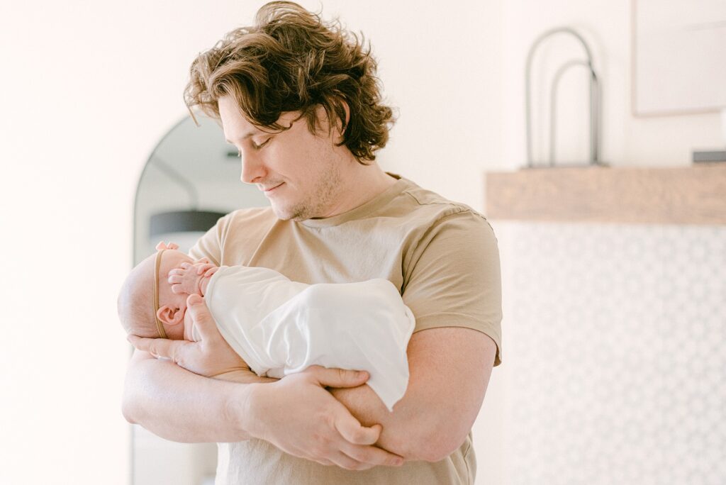 New dad holding newborn baby girl in arms. 