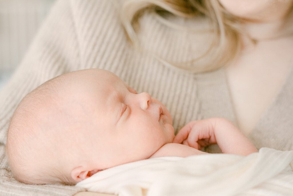 Closeup of newborn baby in mom's arms while sleeping