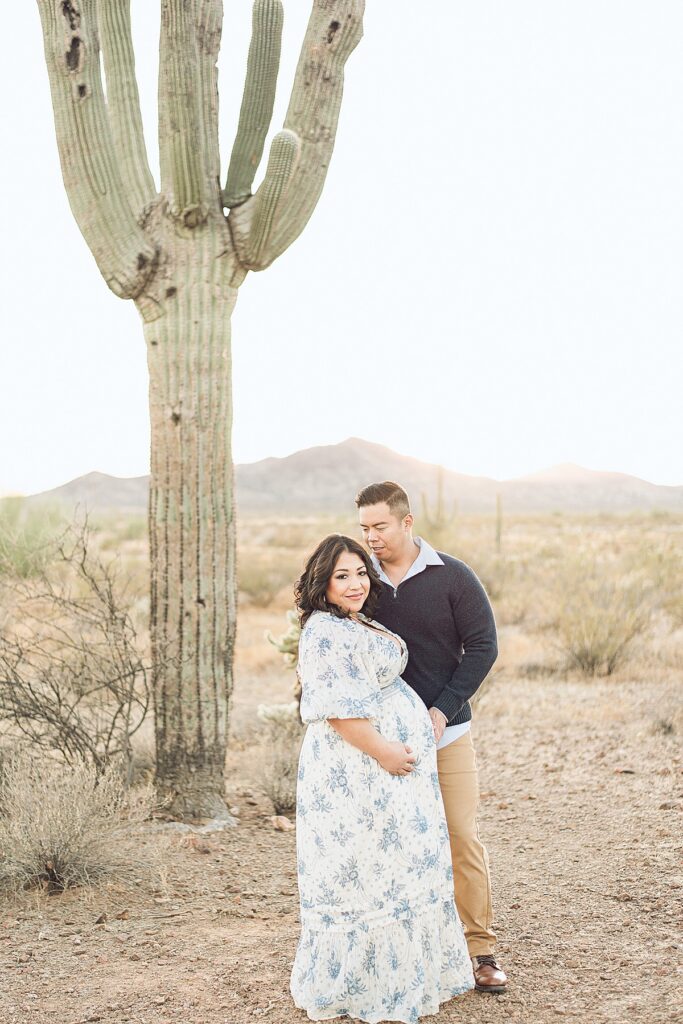 Expecting couple standing next to saguaro cactus in North Phoenix desert