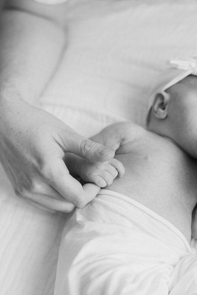 closeup of dad holding newborn baby hand