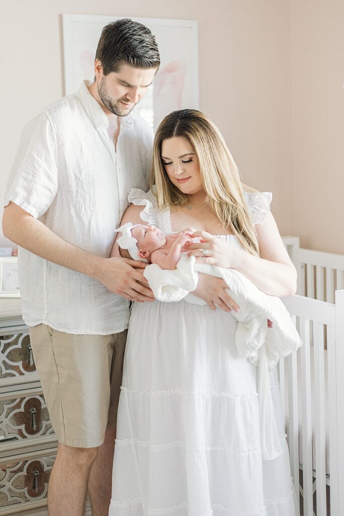 mom and dad in taylor swift inspired nursery. theyre embraced and looking at baby in mom's arms