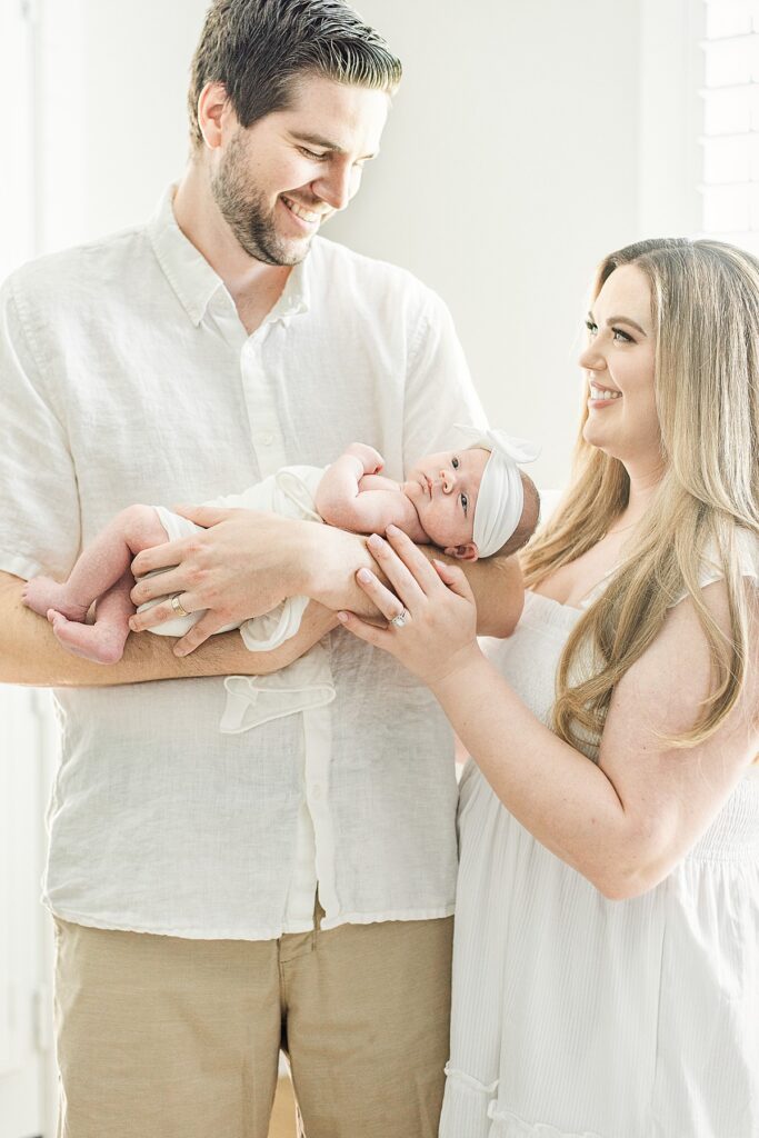 chandler newborn photographer captures new parents holding baby girl and smiling at each other