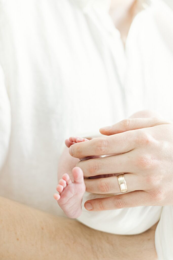 closeup of dad's hand holding newborn baby feet