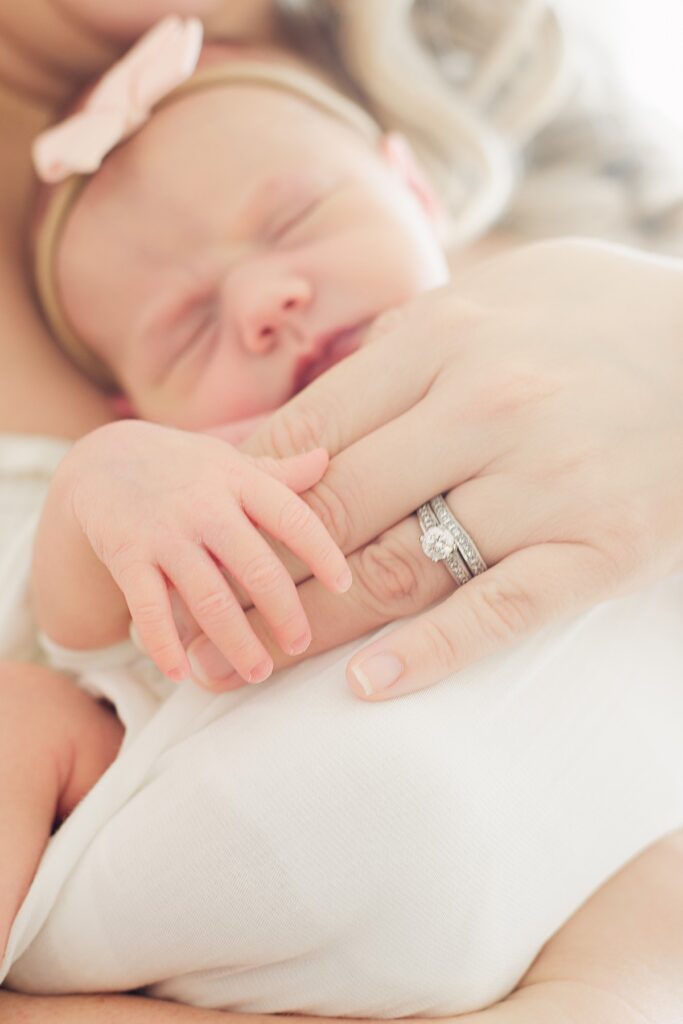 closeup of mom's ring and baby's hand with baby sleeping in the background