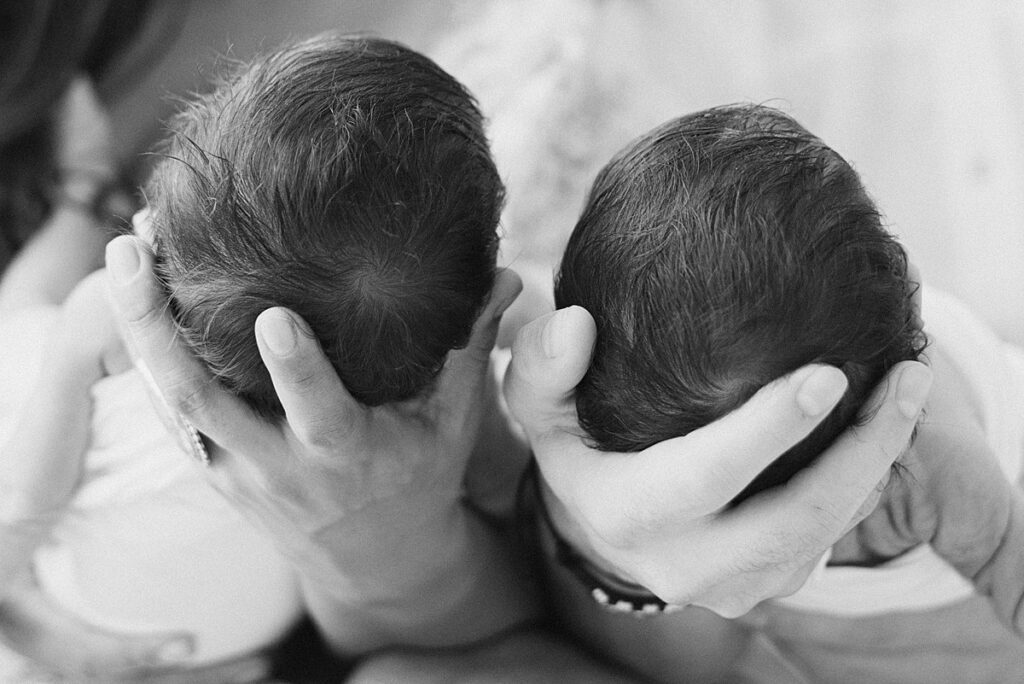 closeup view of twins' heads in the palms of parents hands