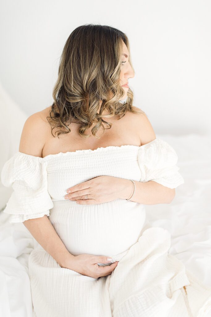 side profile of curls from professional hair and makeup artist for studio maternity photos. mom is cradling bump while looking to the side