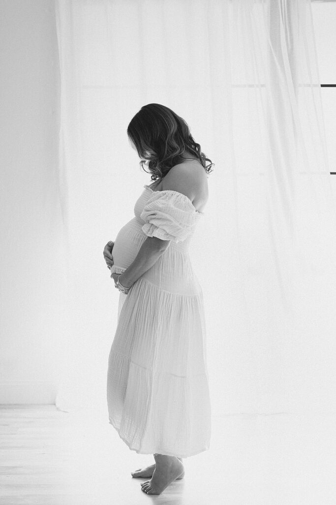side profile of mom with hands on baby bump in 2nd trimester