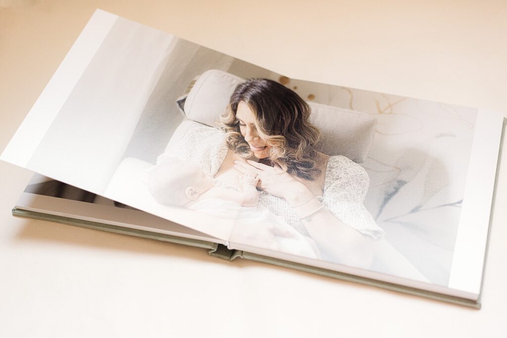 open spread of heirloom album of mom holding baby in nursery