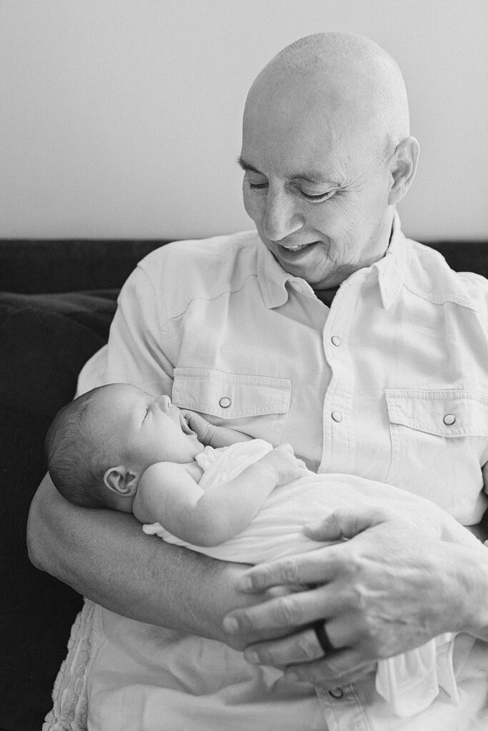 grandfather holding baby who's yawning in his arms