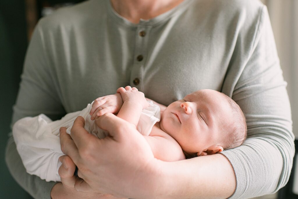 baby boy snuggled in dad's arms for newborn photography in Gilbert, AZ