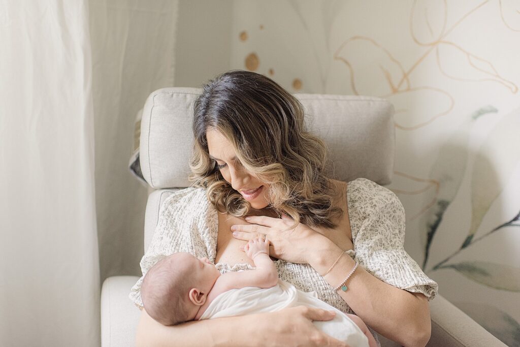mom holding baby in nursery chair
